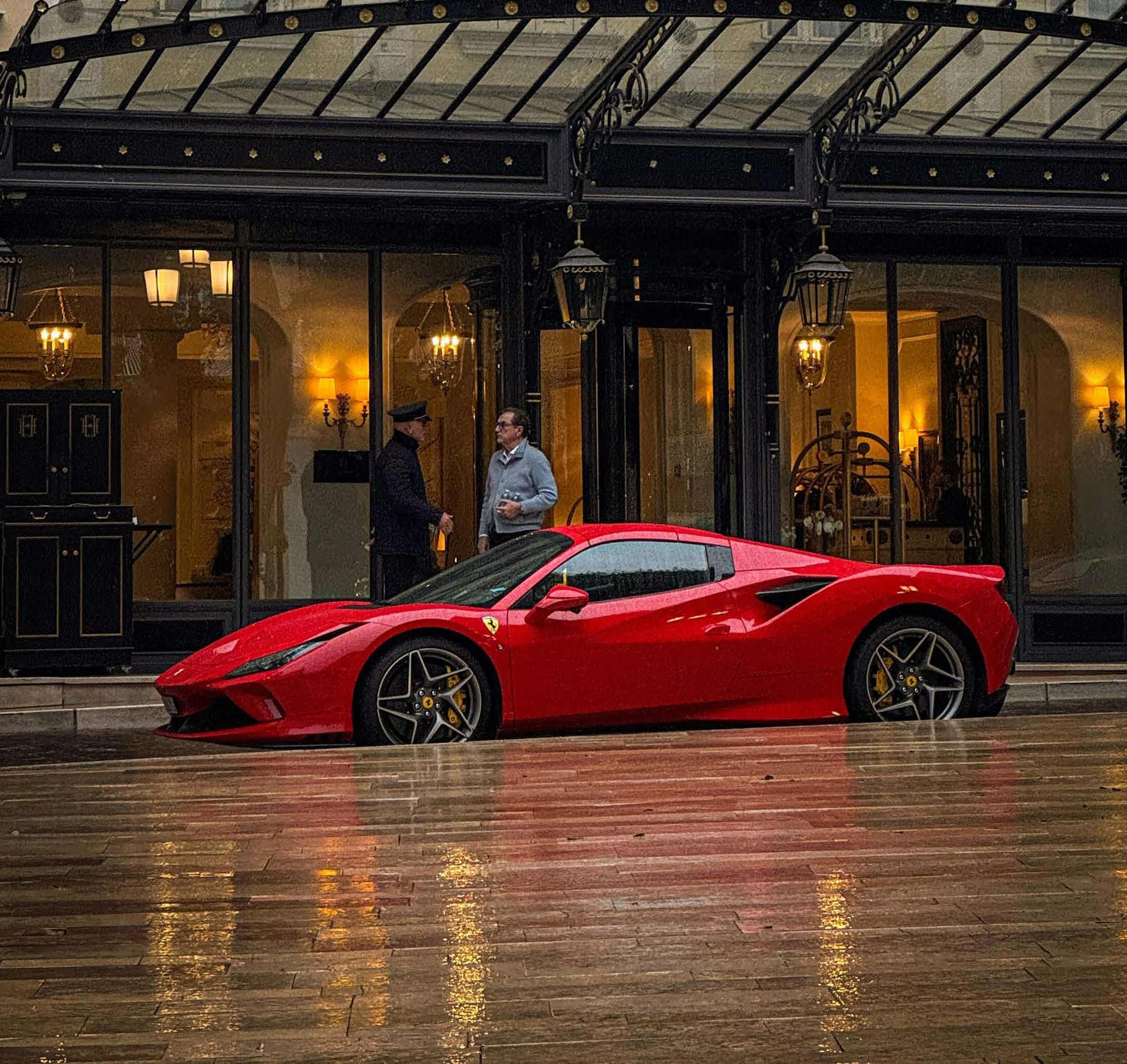 A red Ferrari outside a grand hotel in Monaco at night